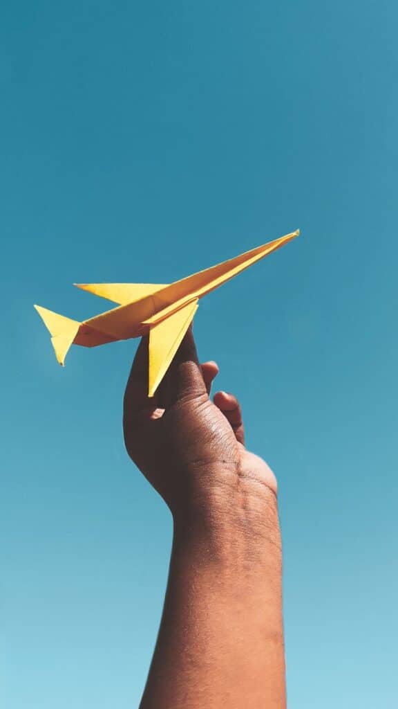 person holding yellow paper plane