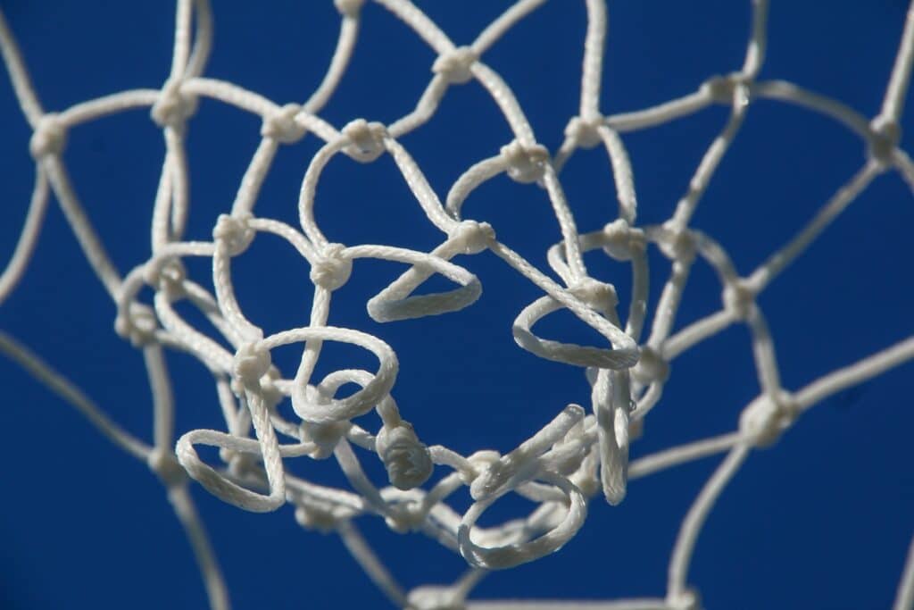 a close up of a basketball net with a blue sky in the background